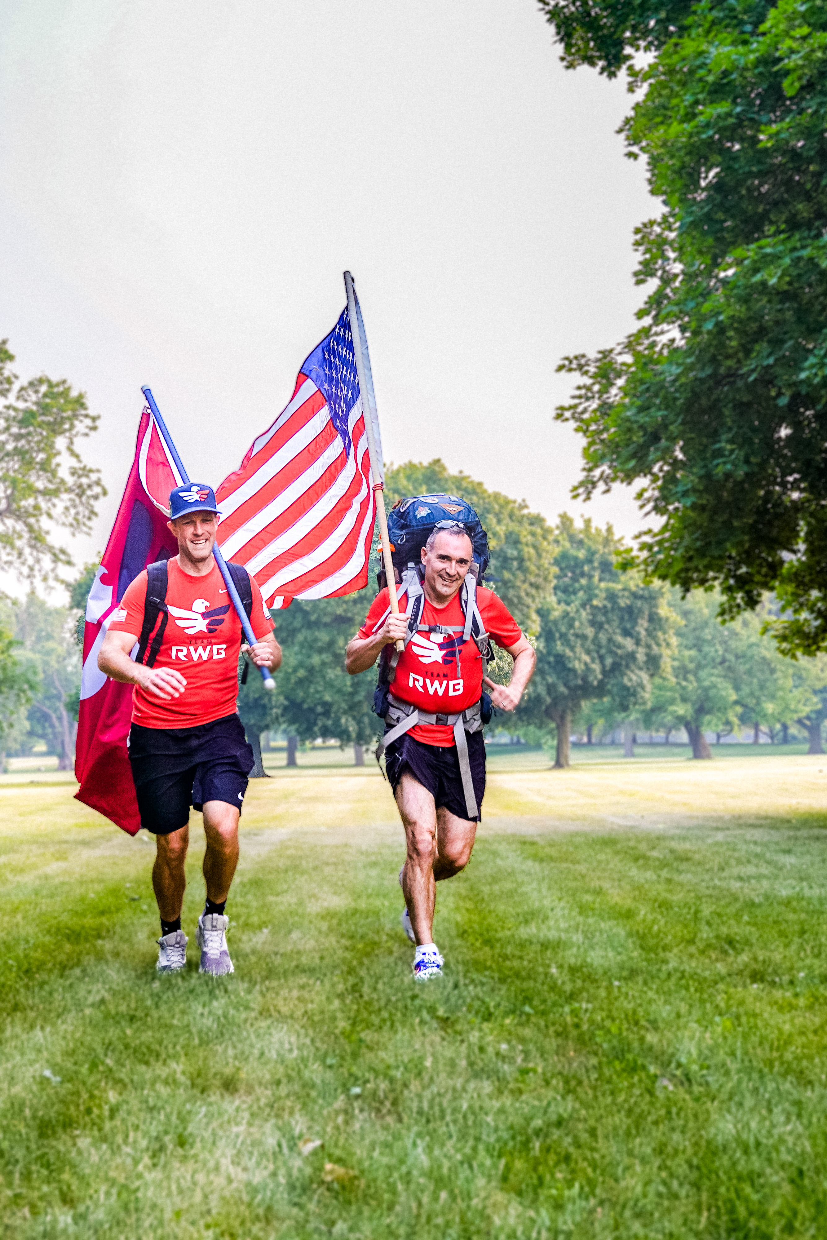 team RWB members running while holding american flags