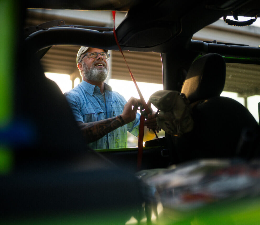 A man loads gear into the back of a vehicle.